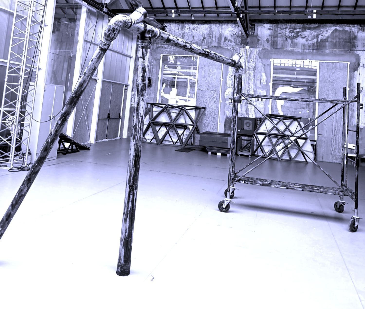 Una figura disfrazada, posiblemente un caballero, sobre zancos, en una habitación poco iluminada con luz azul.